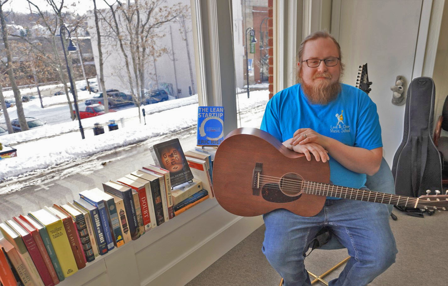 Mike with guitar in his office surrounded by books