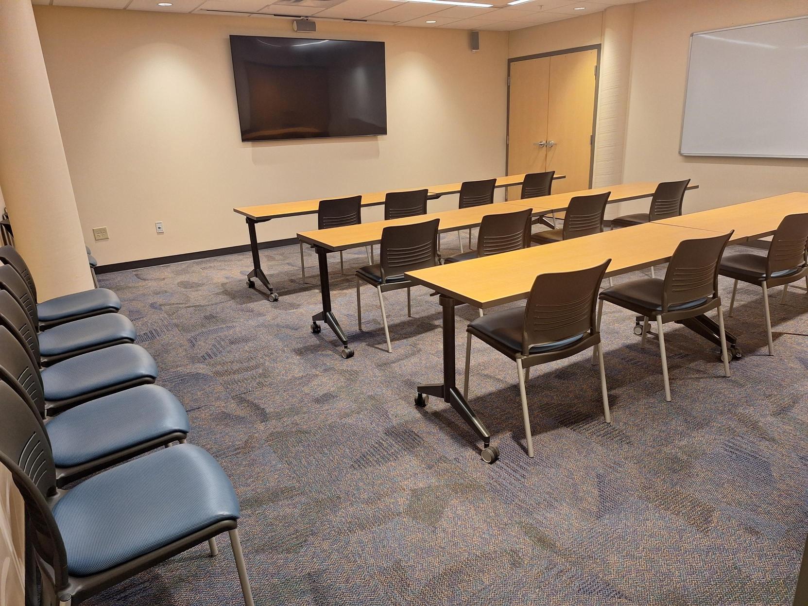 Chambers meeting room set school style with tables, chairs, TV display, and whiteboard