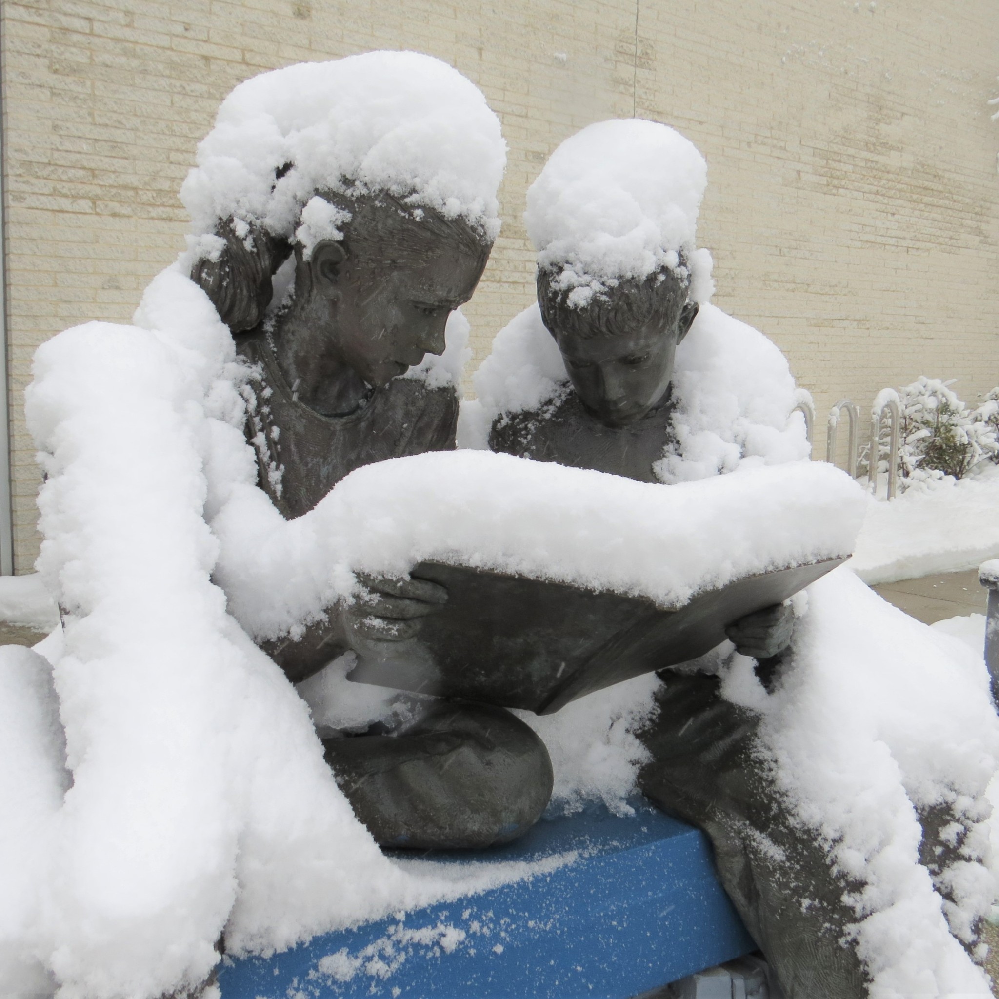 Statue of Children reading with snow on it