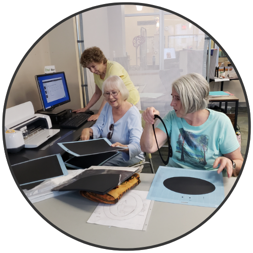 Three senior ladies working at a cricut machine and computer in the makerspace.