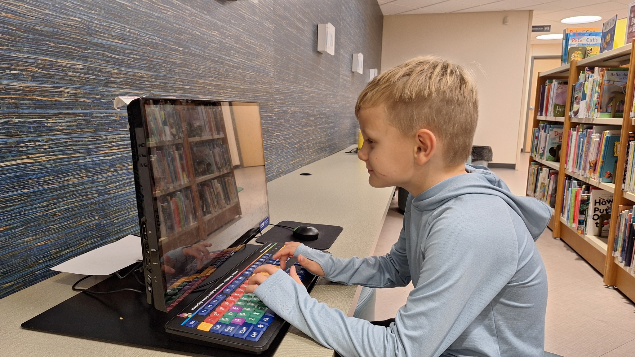 A boy on a educational game computer in the children's department.