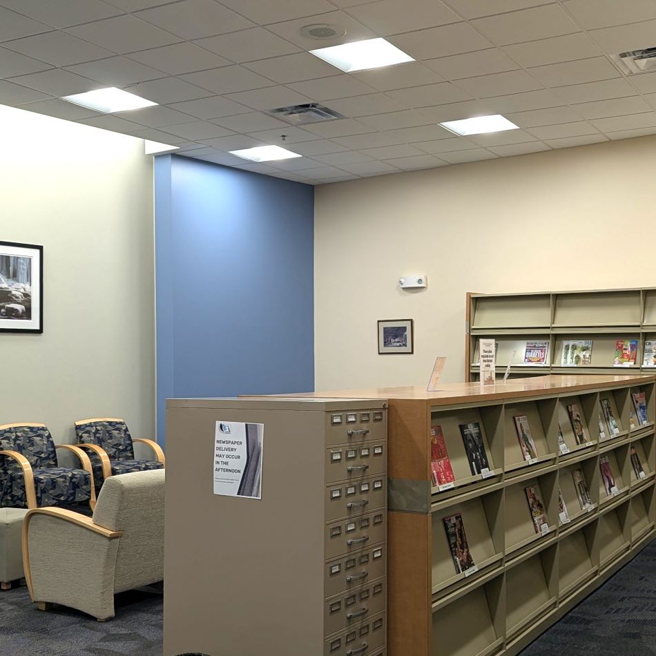 Room with shelves of magazines and chairs.