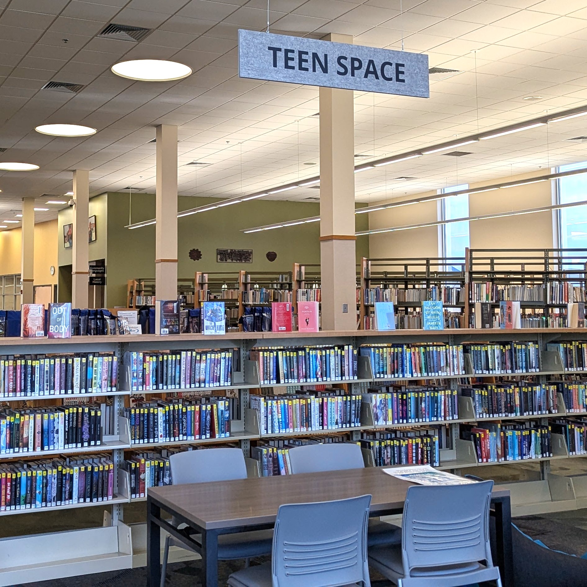 Rows of shelves with a hanging sign that says Teen Space above them.