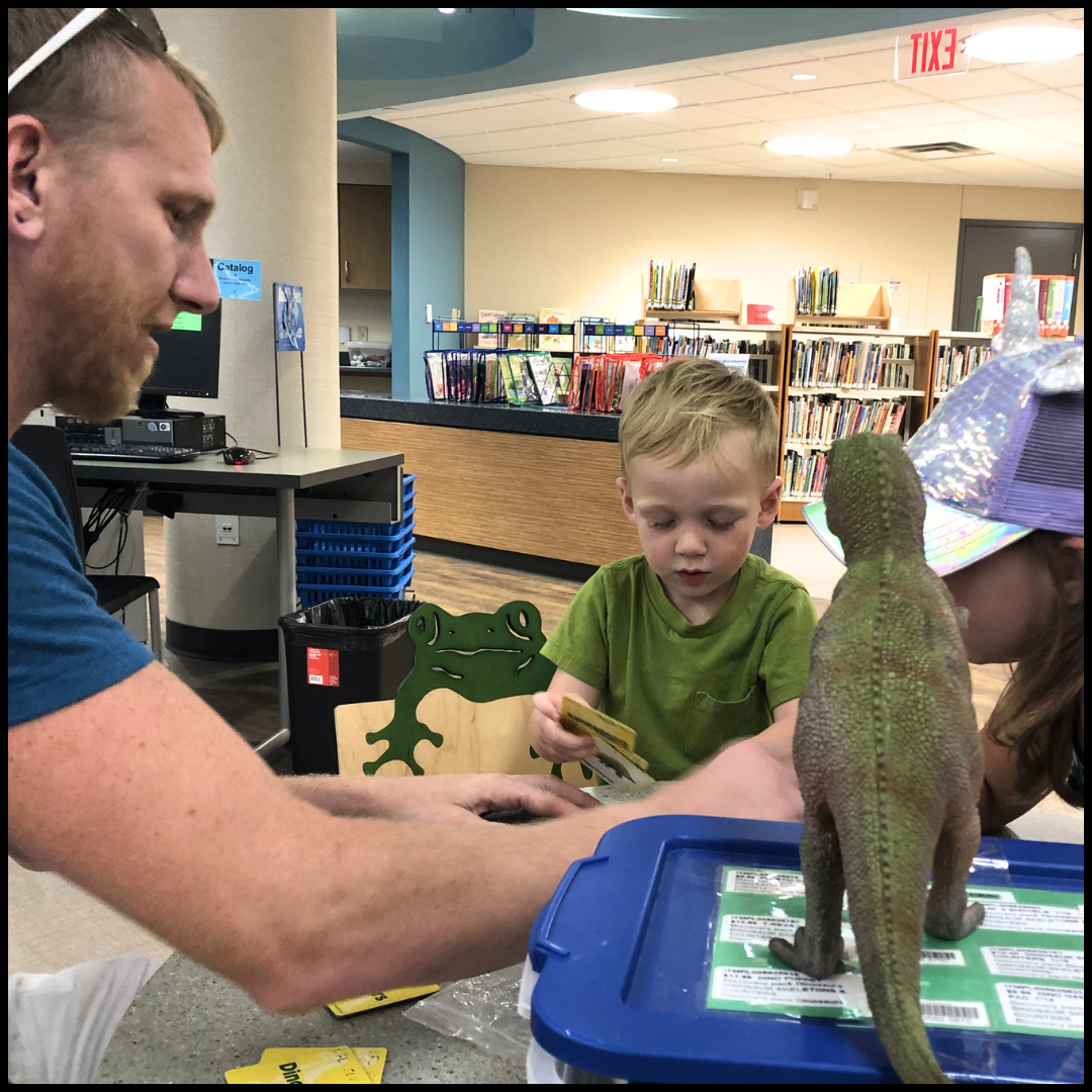A man playing with his two kids in the Children's Department.